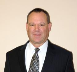 Photo of a man in a white shirt, tie and black jacket